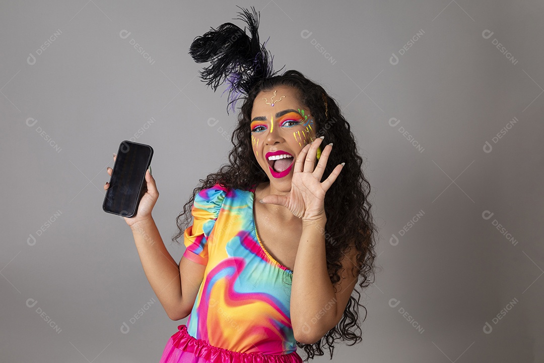 Linda morena do cabelo cacheado sorridente fantasiada segurando smartphone sobre fundo isolado