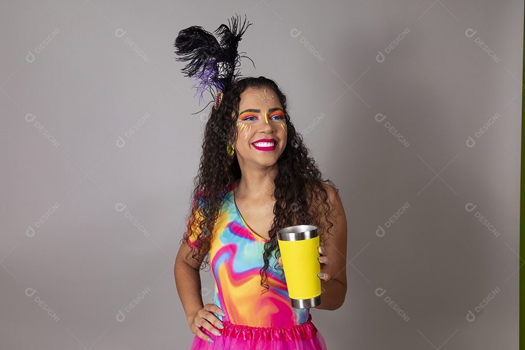 Linda morena do cabelo cacheado sorridente fantasiada segurando copo amarelo sobre fundo isolado