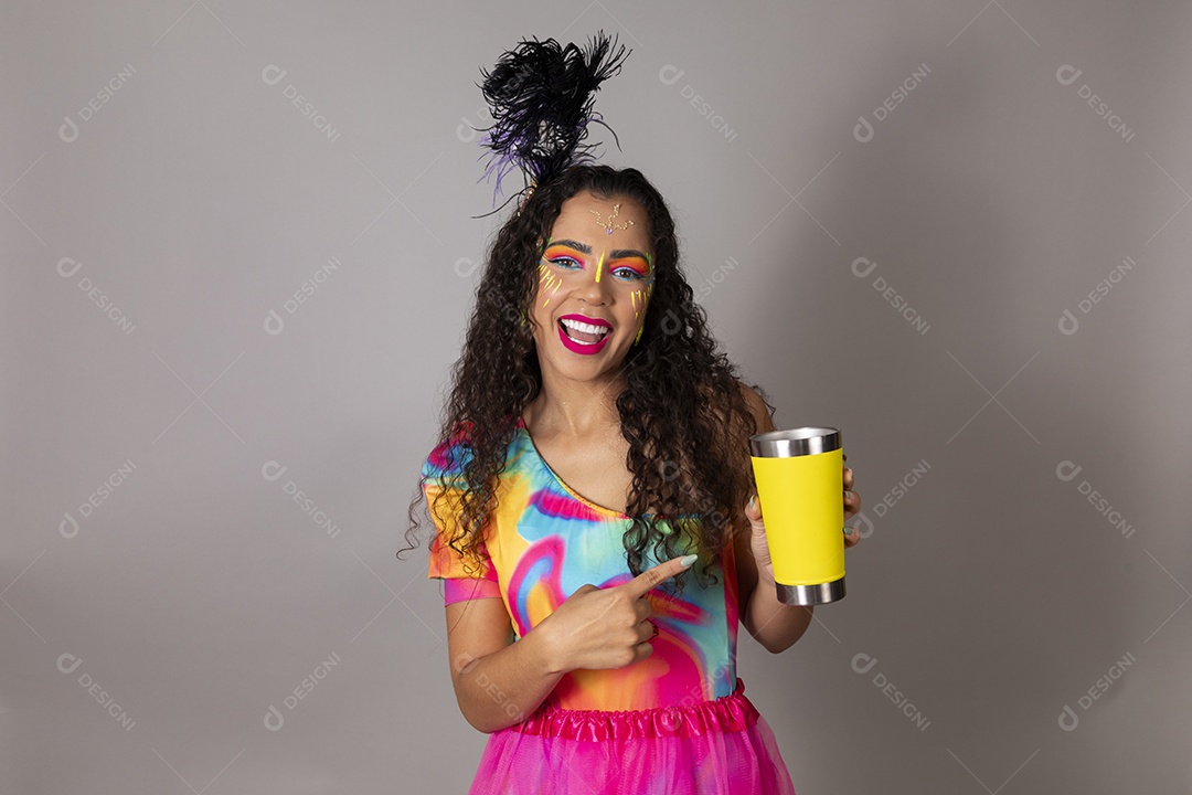 Linda morena do cabelo cacheado sorridente fantasiada segurando copo amarelo sobre fundo isolado