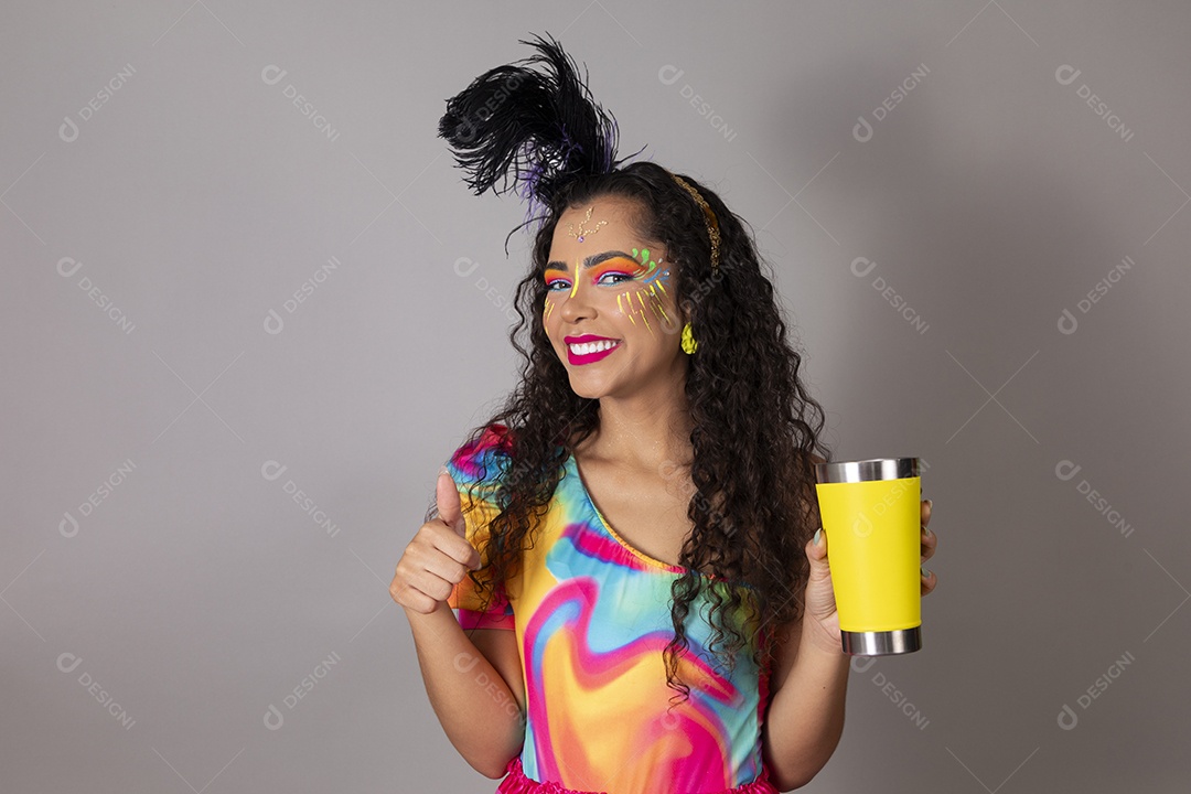 Linda morena do cabelo cacheado sorridente fantasiada segurando copo amarelo sobre fundo isolado