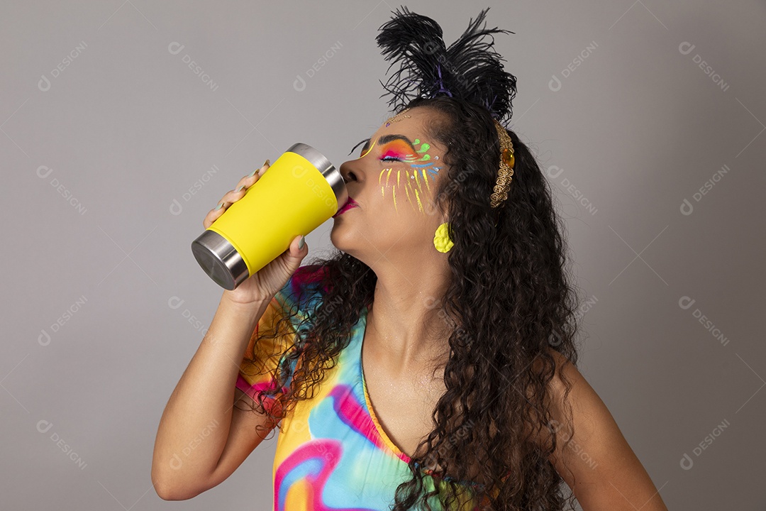 Linda morena do cabelo cacheado sorridente fantasiada segurando copo amarelo sobre fundo isolado