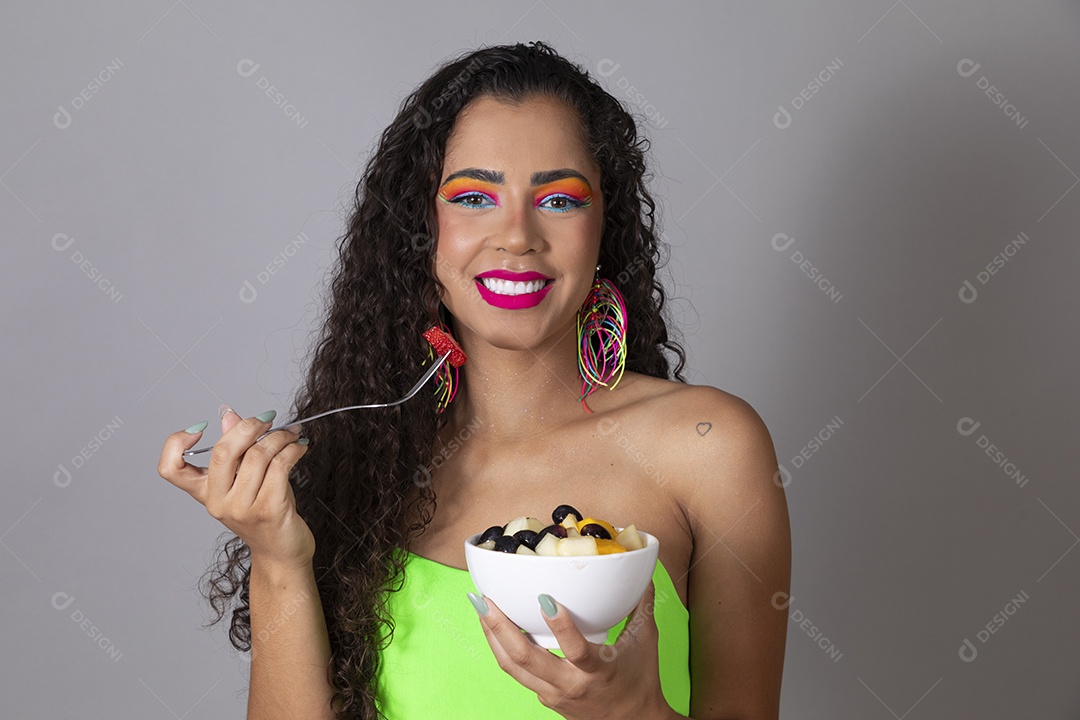 Linda morena do cabelo cacheado sorridente fantasiada segurando tijela de sorvete sobre fundo isolado