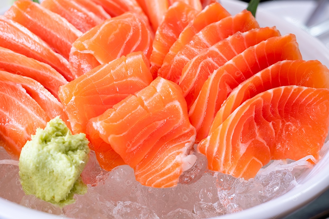 Fatia de salmão cru ou sashimi de salmão e wasabi no estilo japonês servido fresco no gelo em uma tigela branca