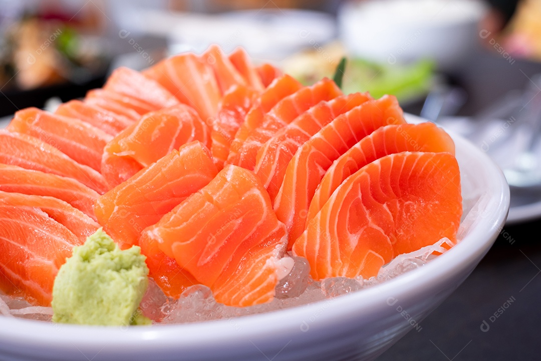 Fatia de salmão cru ou sashimi de salmão e wasabi no estilo japonês servido fresco no gelo em uma tigela branca