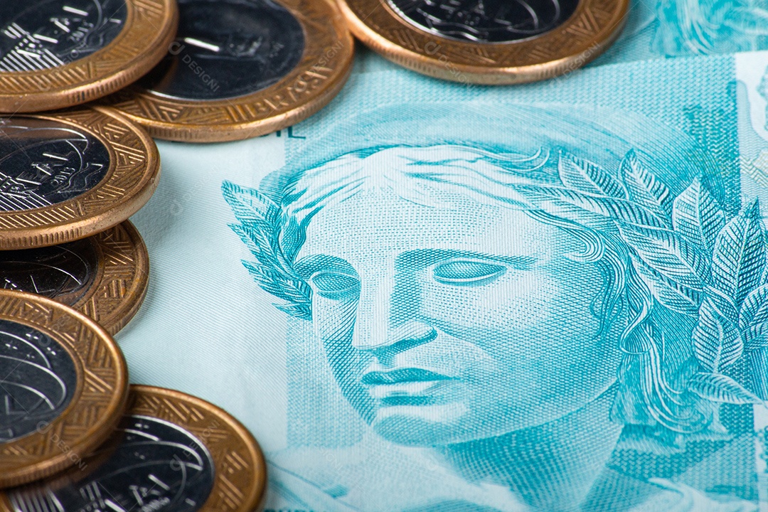 Notas e moedas de real brasileiro com uma caneta