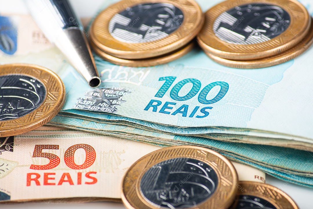 Notas e moedas de real brasileiro com uma caneta