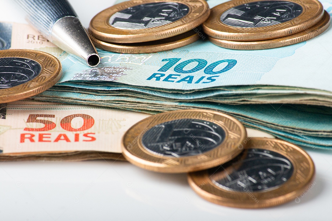 Notas e moedas de real brasileiro com uma caneta