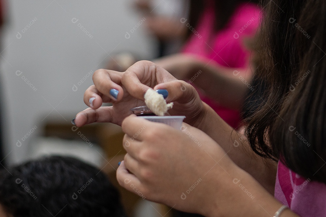 Mão de uma pessoa segurando copo de vinho e pão para ceia