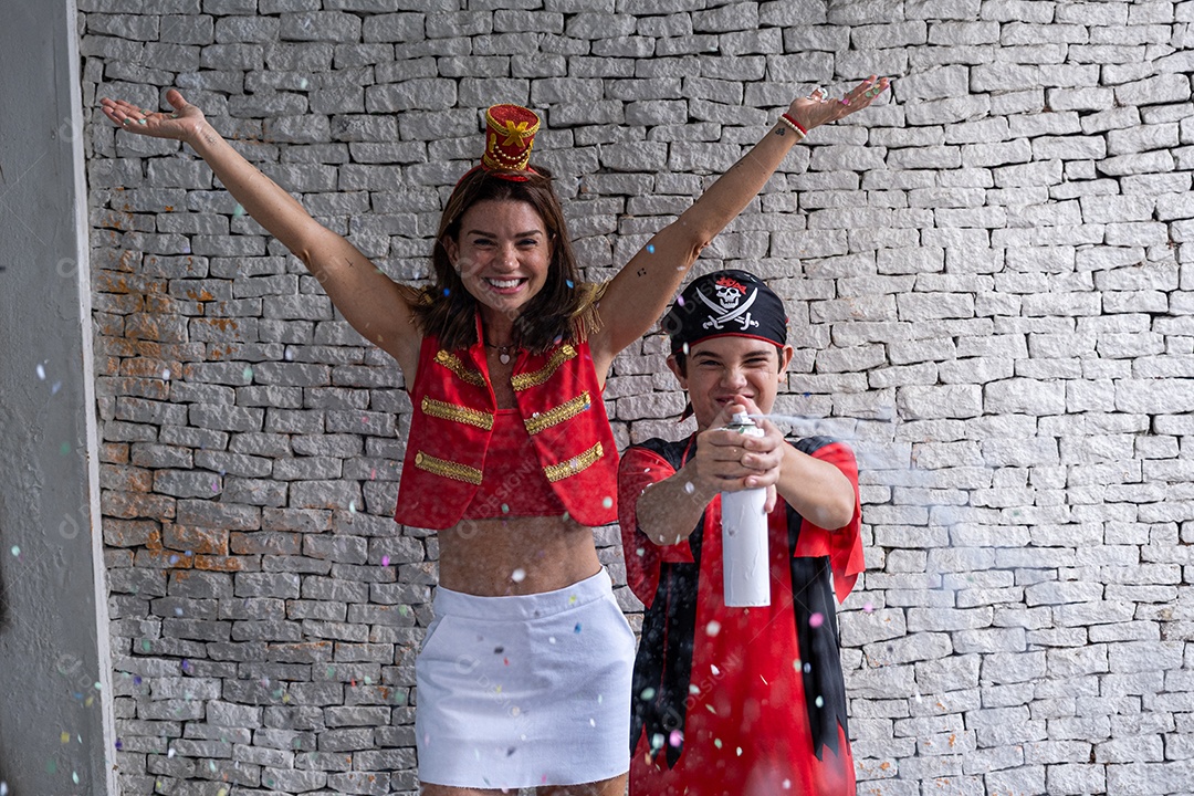 Mãe e filho fantasiados e brincando com confete e espuma de festa