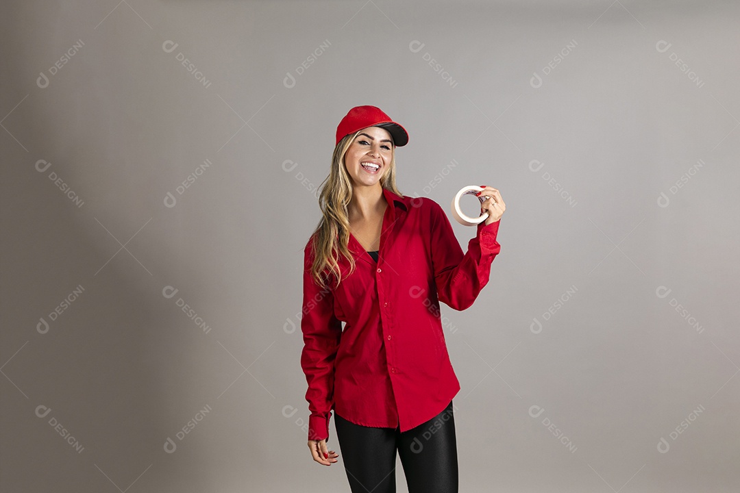 Bela mulher sorridente usando boné segurando fita isolante em branco sobre fundo isolado