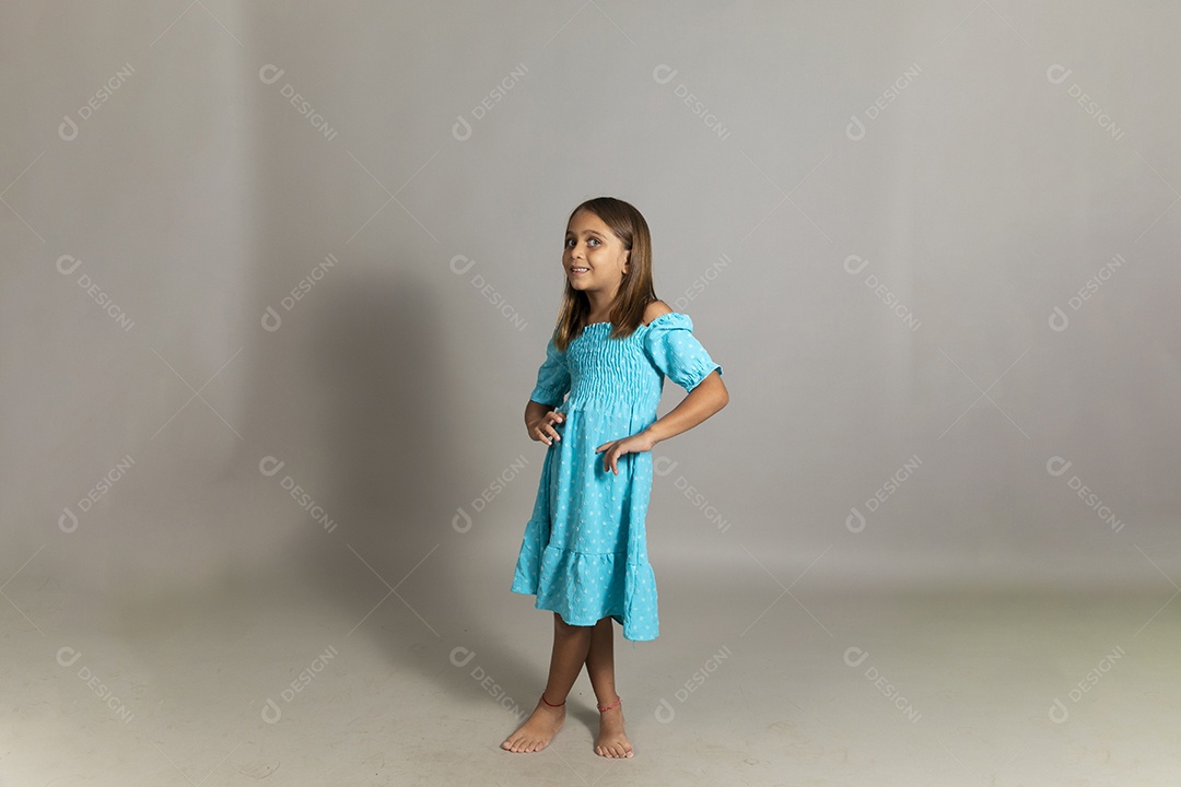Linda garotinha usando vestido longo azul sorridente fazendo pose sobre fundo isolado