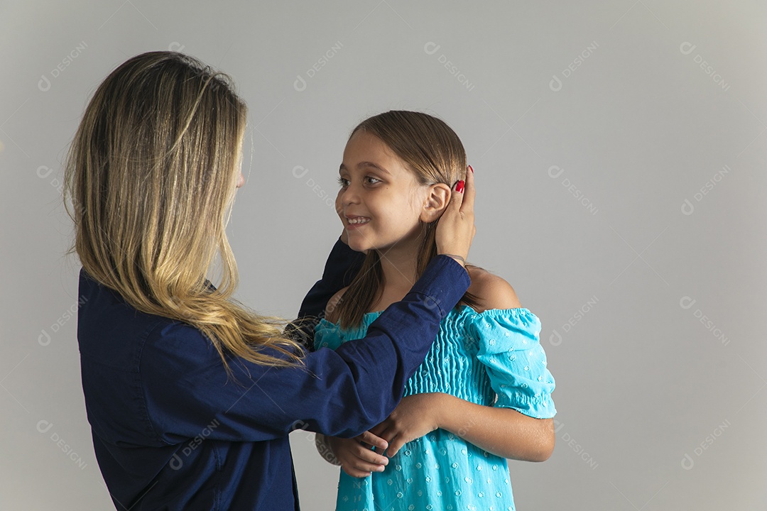 Belo retrato de mãe e filha sorridente fazendo pose sobre fundo isolado