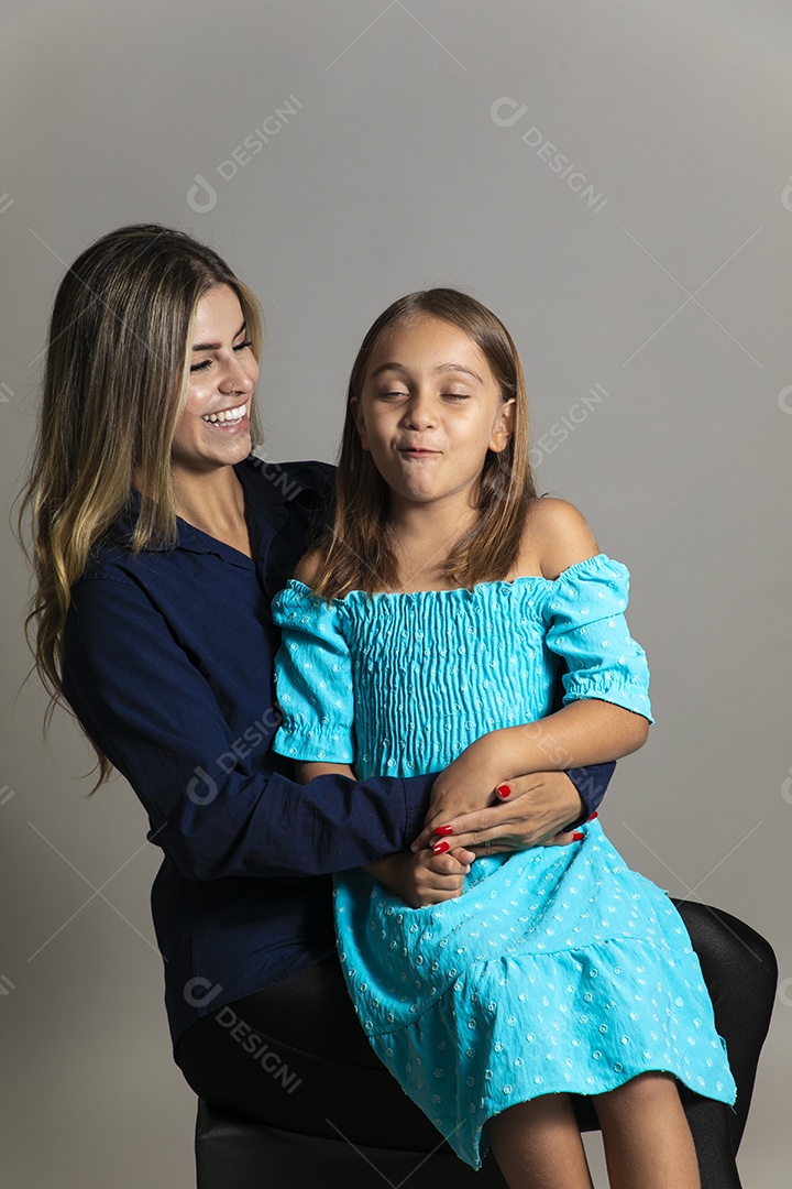 Belo retrato de mãe e filha sorridente fazendo pose sobre fundo isolado