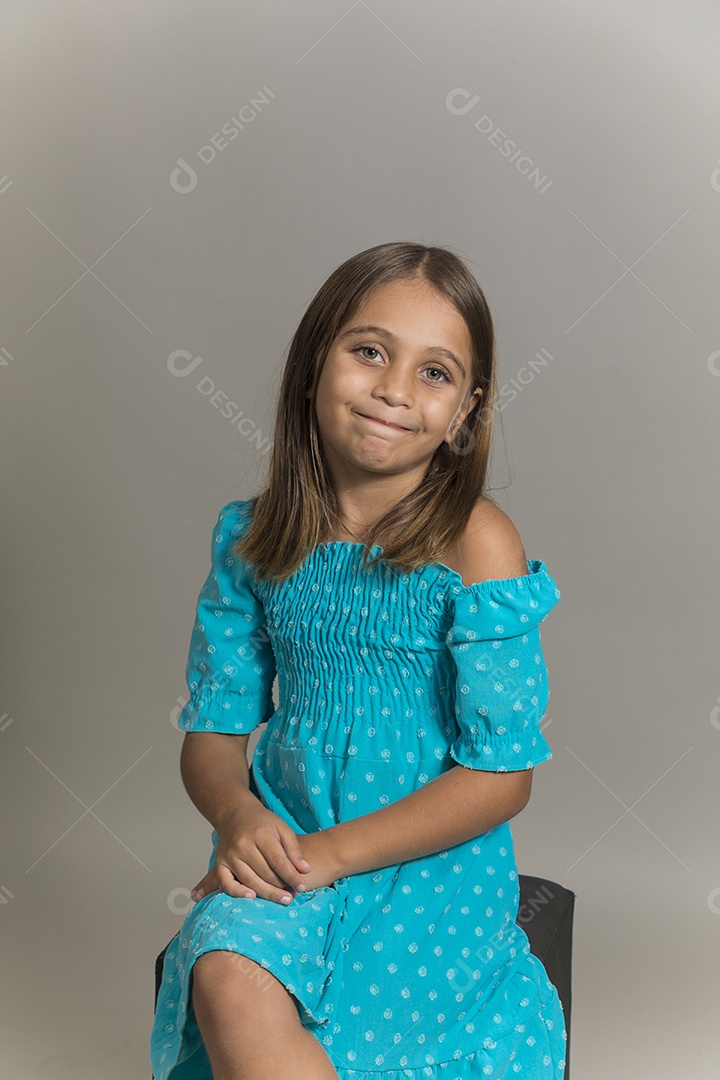 Linda garotinha sentada de pernas cruzadas sobre fundo isolado