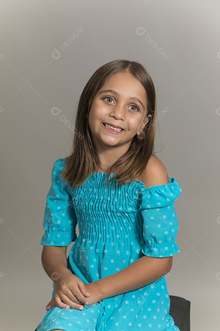 Linda garotinha sentada de pernas cruzadas sobre fundo isolado