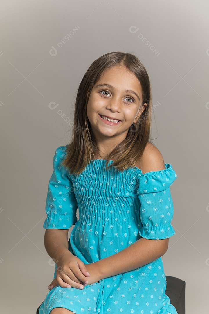 Linda garotinha sentada de pernas cruzadas sobre fundo isolado