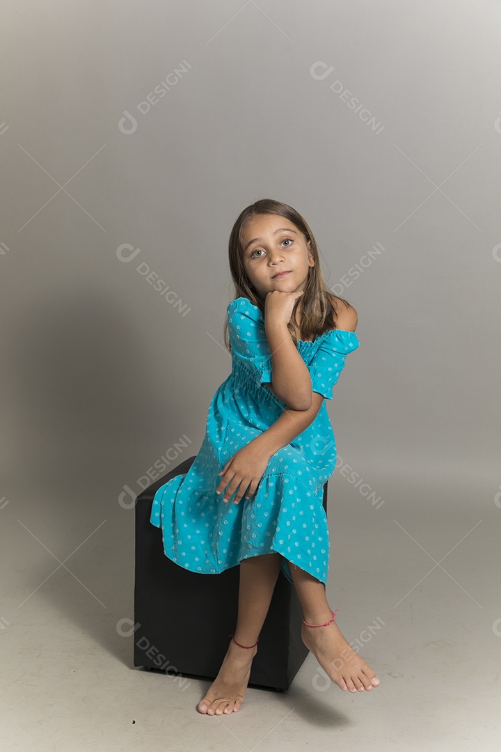 Linda garotinha sentada de pernas cruzadas sobre fundo isolado