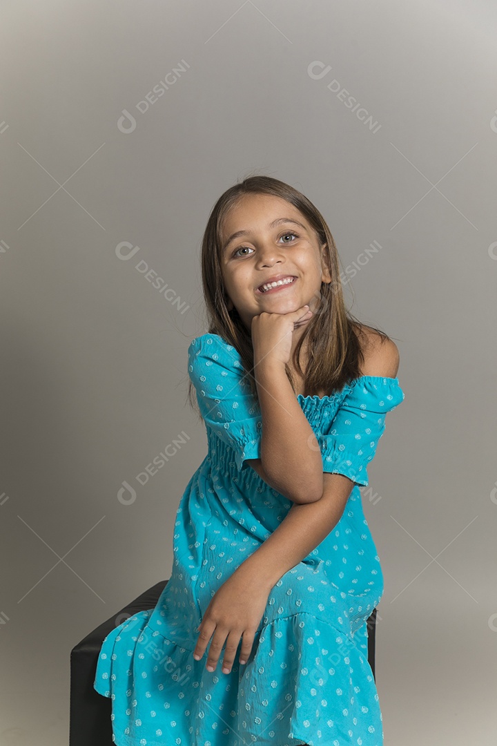 Linda garotinha sentada de pernas cruzadas sobre fundo isolado