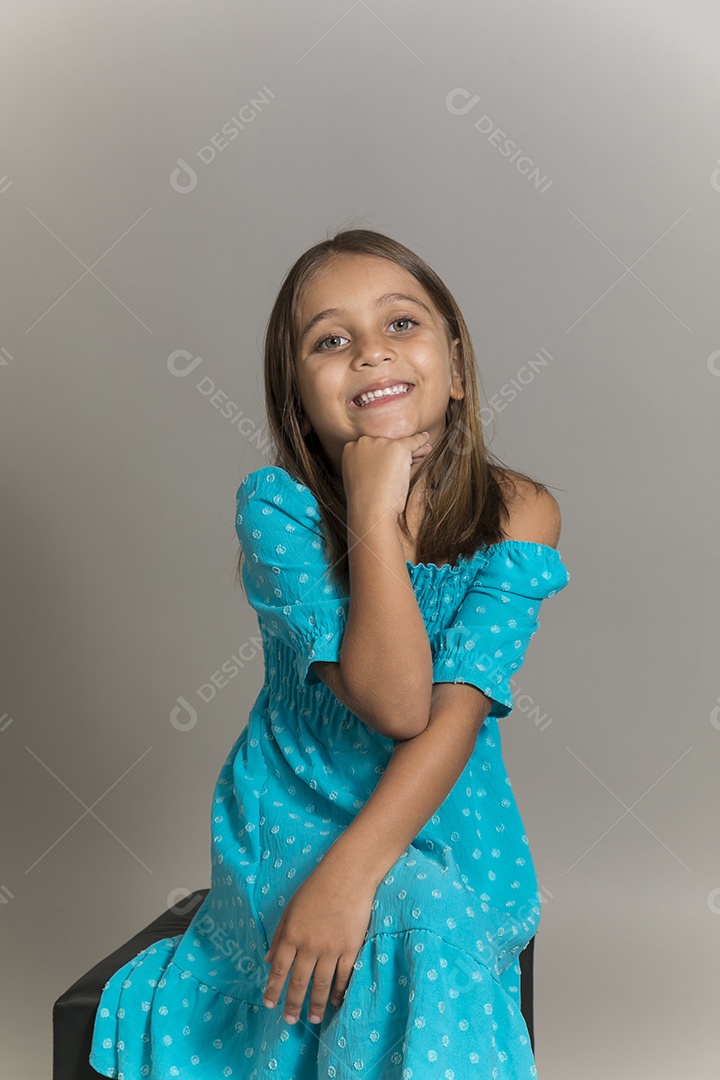 Linda garotinha sentada de pernas cruzadas sobre fundo isolado