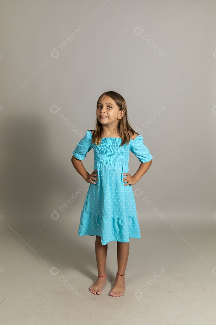 Linda garotinha usando vestido longo azul fazendo pose sobre fundo isolado