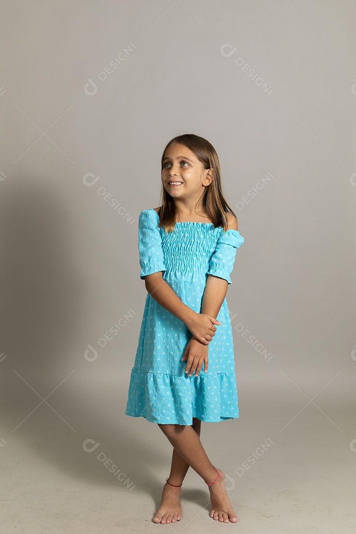 Linda garotinha usando vestido longo azul fazendo pose sobre fundo isolado