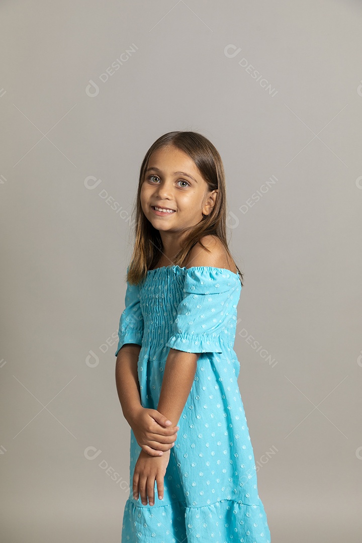Linda garotinha usando vestido longo azul fazendo pose sobre fundo isolado