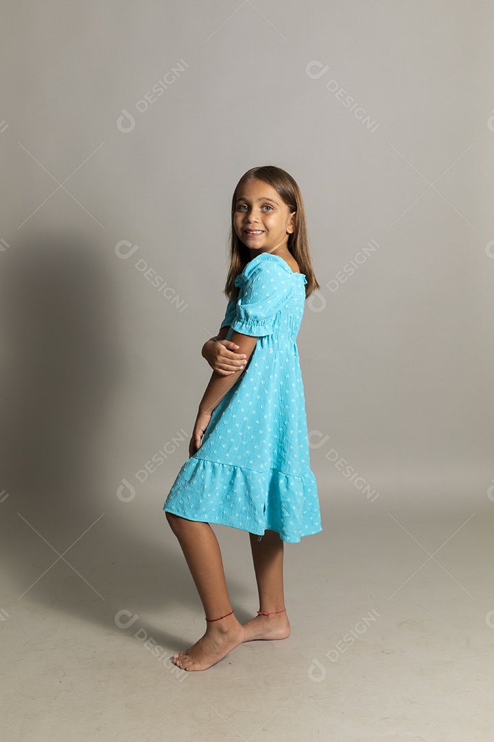 Linda garotinha usando vestido longo azul fazendo pose sobre fundo isolado