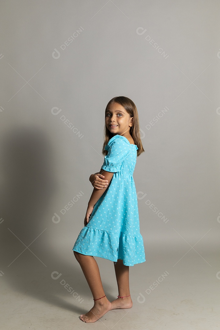 Linda garotinha usando vestido longo azul fazendo pose sobre fundo isolado