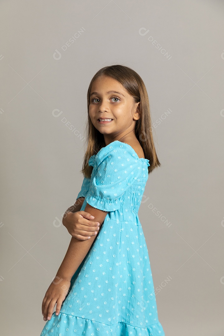 Linda garotinha usando vestido longo azul fazendo pose sobre fundo isolado