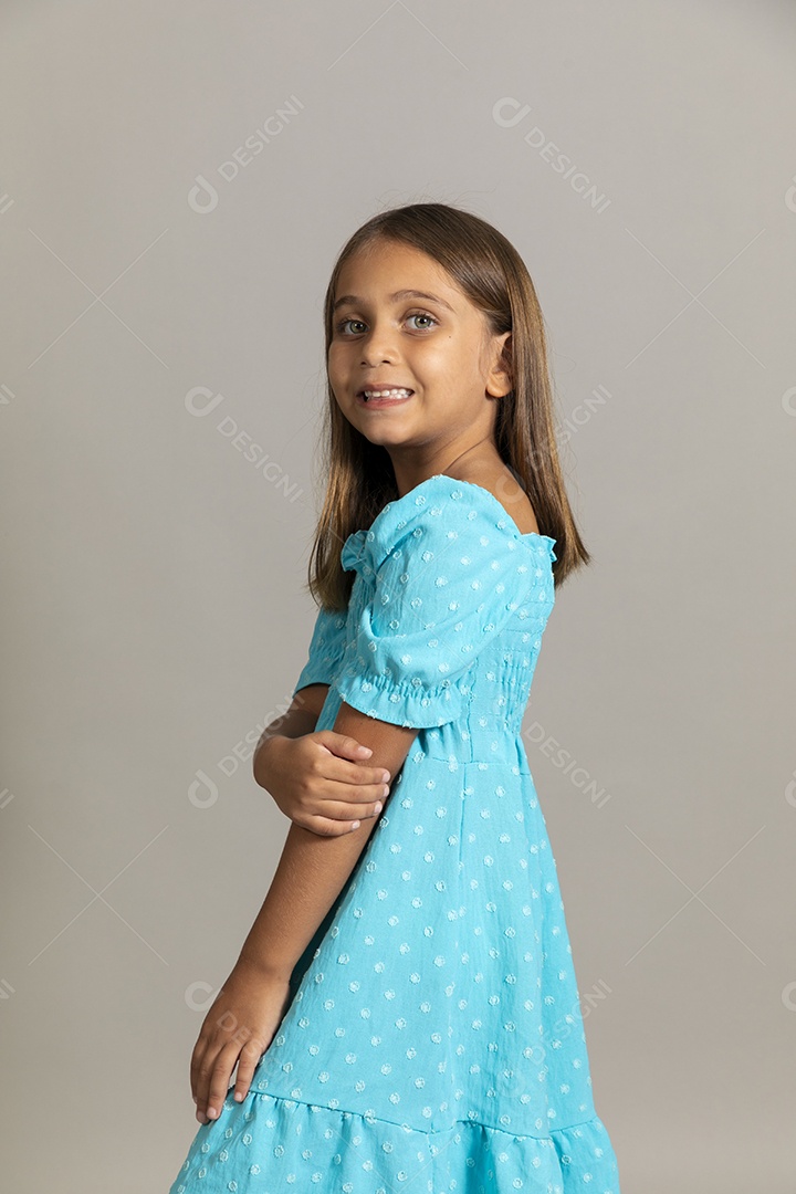 Linda garotinha usando vestido longo azul fazendo pose sobre fundo isolado