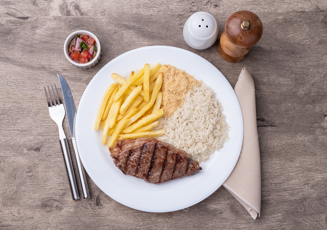 A imagem mostra um prato de comida que inclui um bife, batatas fritas, arroz e feijão