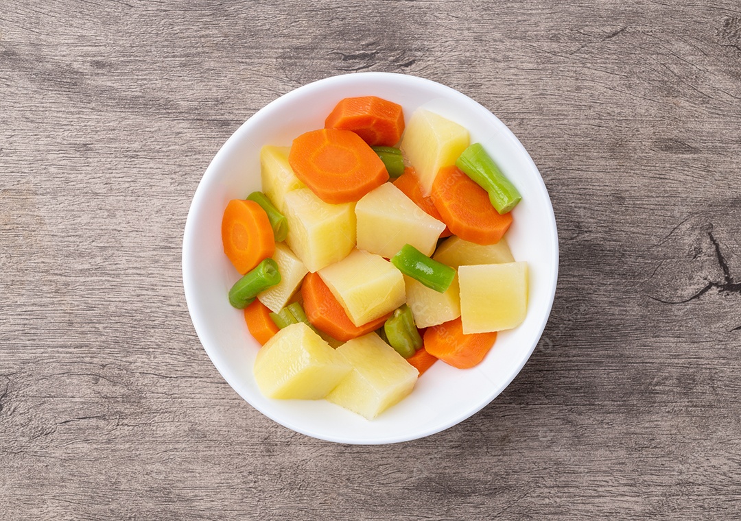 A imagem mostra um prato de legumes cozidos, principalmente batatas e cenouras em cubos
