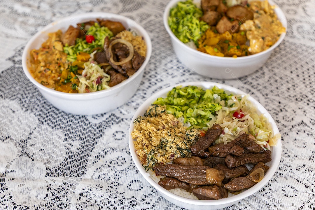 Belas refeições em marmitex branca sobre mesa de marmore escura