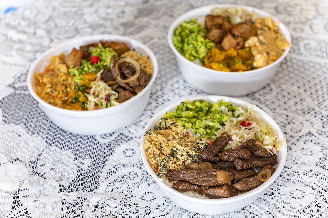 Belas refeições em marmitex branca sobre mesa de marmore escura