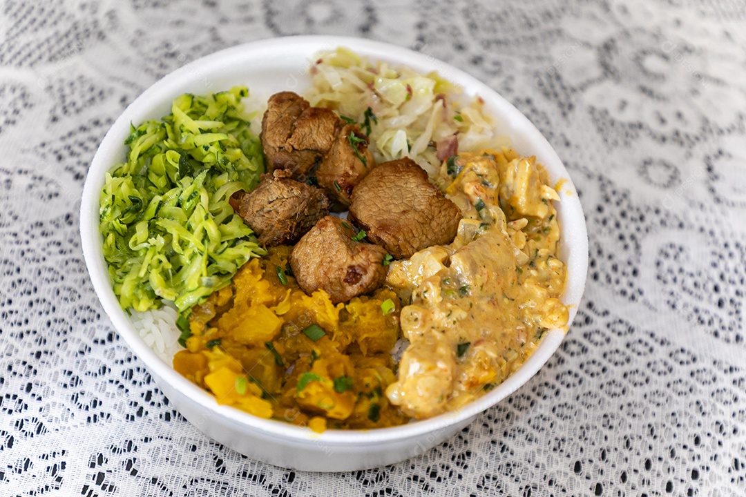 Bela refeição em uma marmitex branca sobre mesa de marmore escura