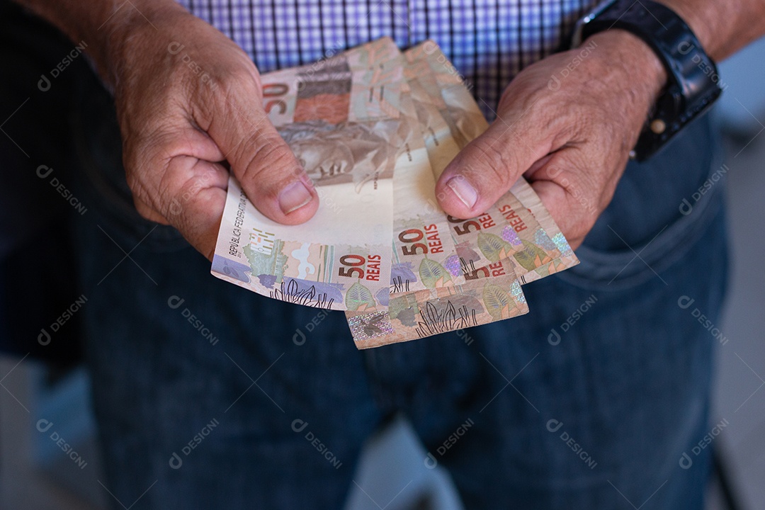 Homem segurando notas de real brasileiro na mão