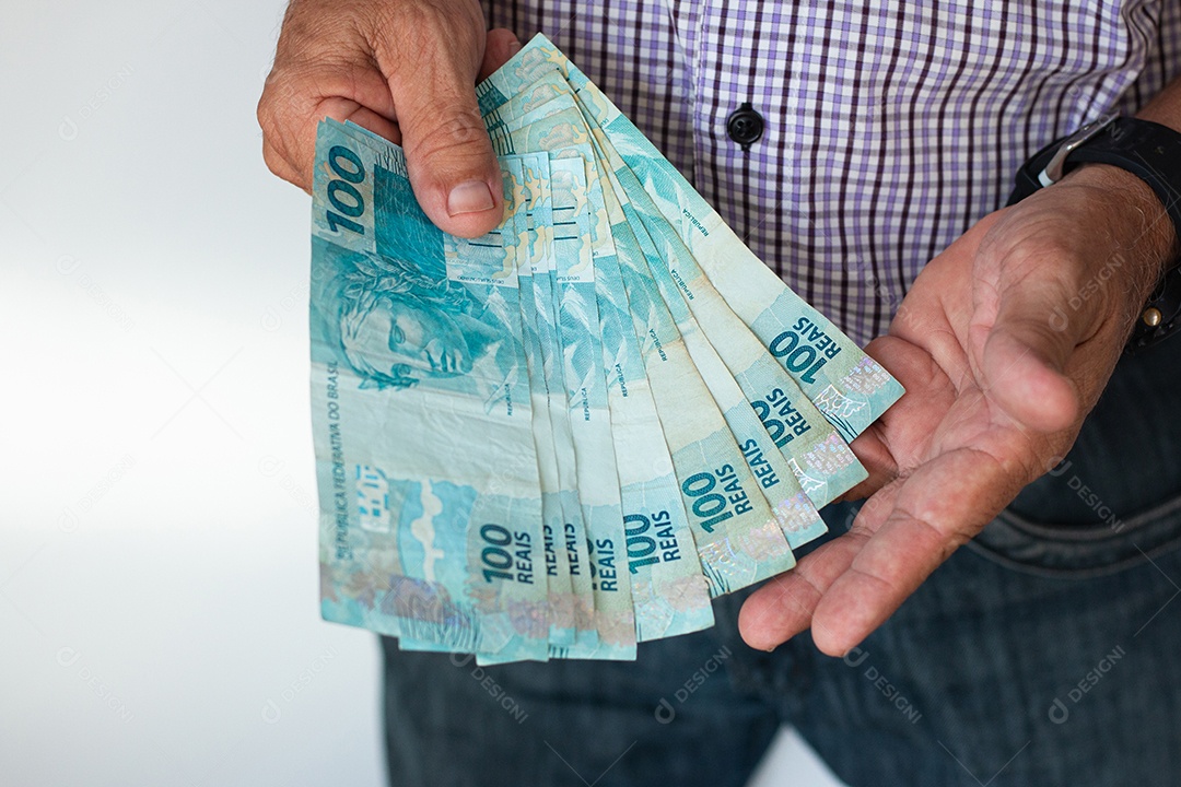 Homem segurando notas de real brasileiro na mão
