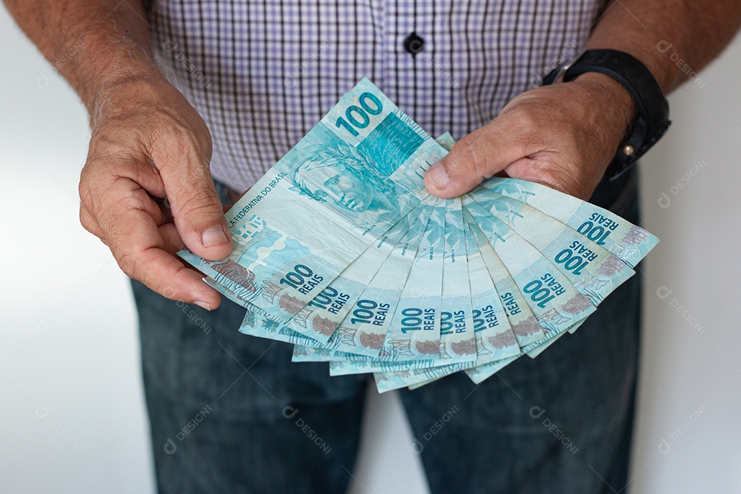 Homem segurando notas de real brasileiro e carteira