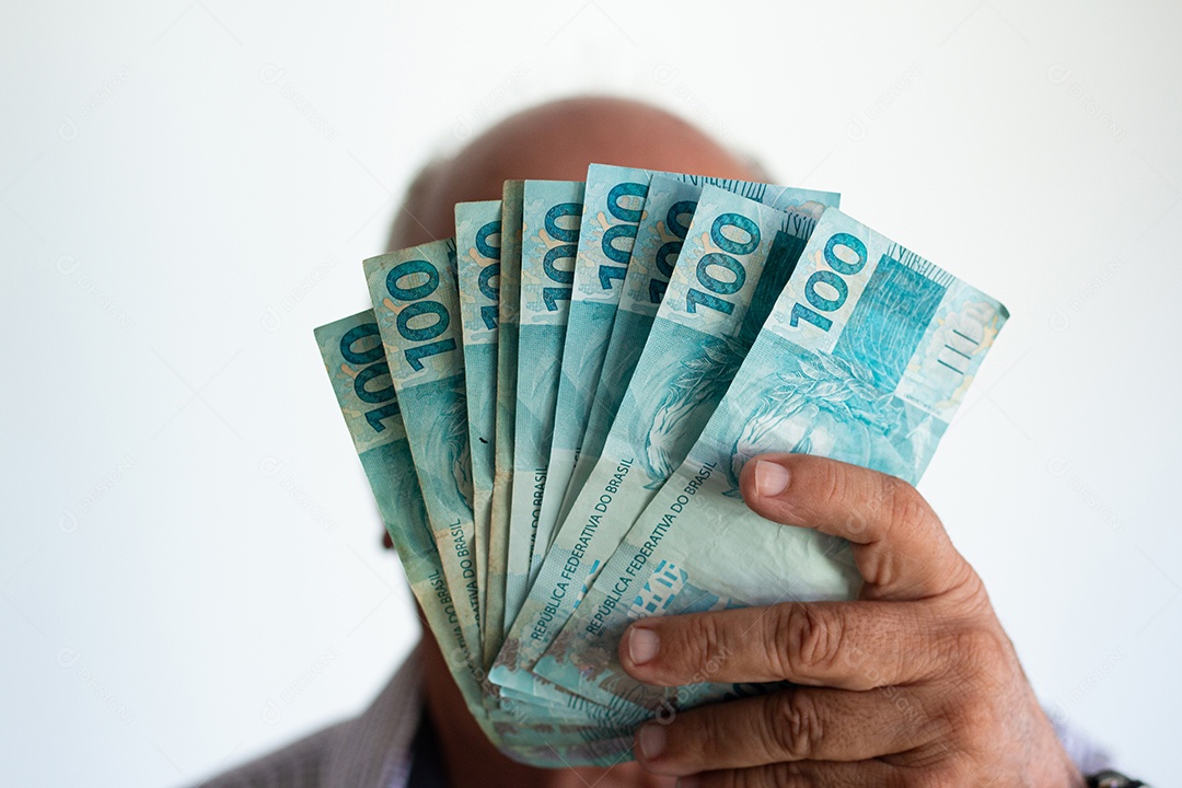 Homem segurando notas de real brasileiro na mão