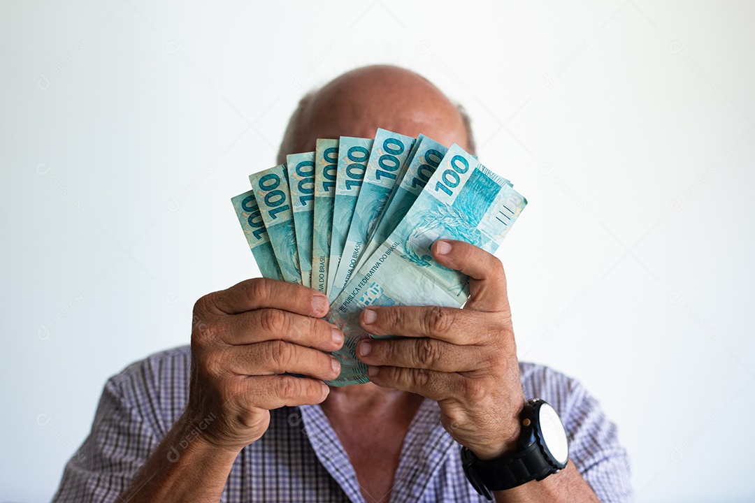 Homem segurando notas de real brasileiro na mão