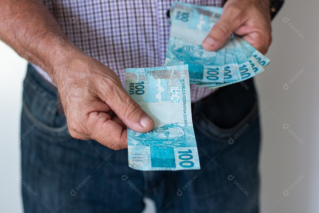 Mão segurando notas de real dinheiro brasileiro