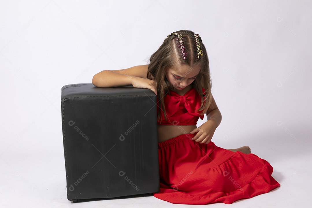 Linda menina sentada com look vermelho sobre fundo de studio isolado