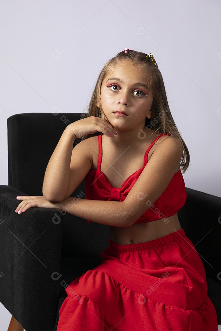 Linda menina sentada com look vermelho sobre fundo de studio isolado