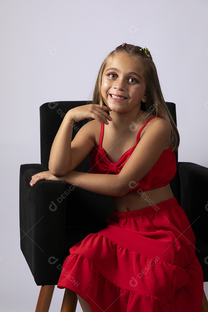 Linda menina sentada com look vermelho sobre fundo de studio isolado