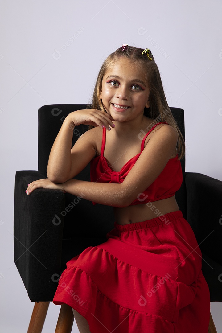 Linda menina sentada com look vermelho sobre fundo de studio isolado