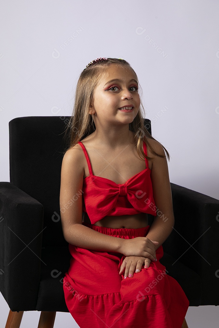 Linda menina sentada com look vermelho sobre fundo de studio isolado