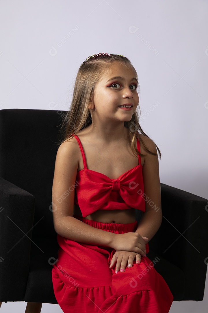 Linda menina sentada com look vermelho sobre fundo de studio isolado