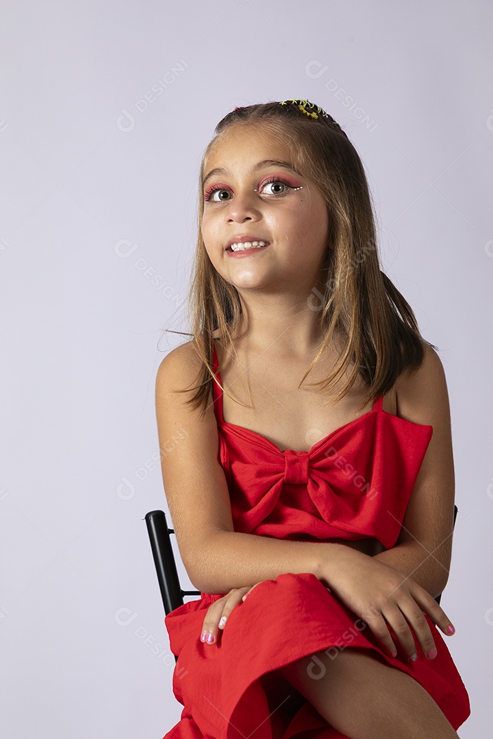 Linda menina sentada com look vermelho sobre fundo de studio isolado