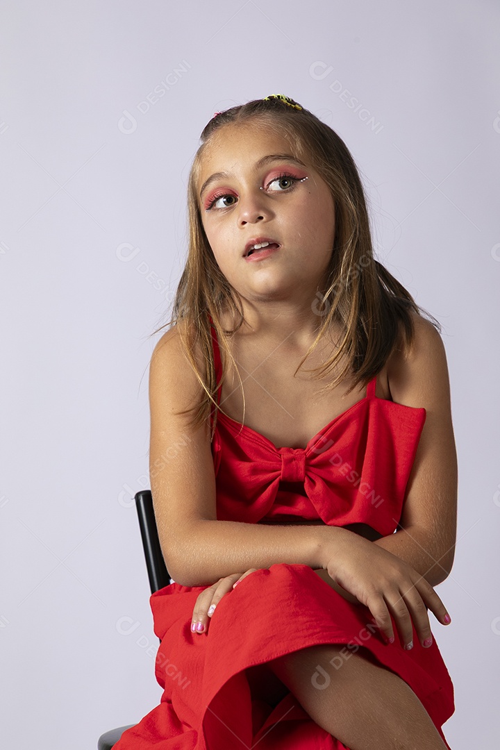 Linda menina sentada com look vermelho sobre fundo de studio isolado