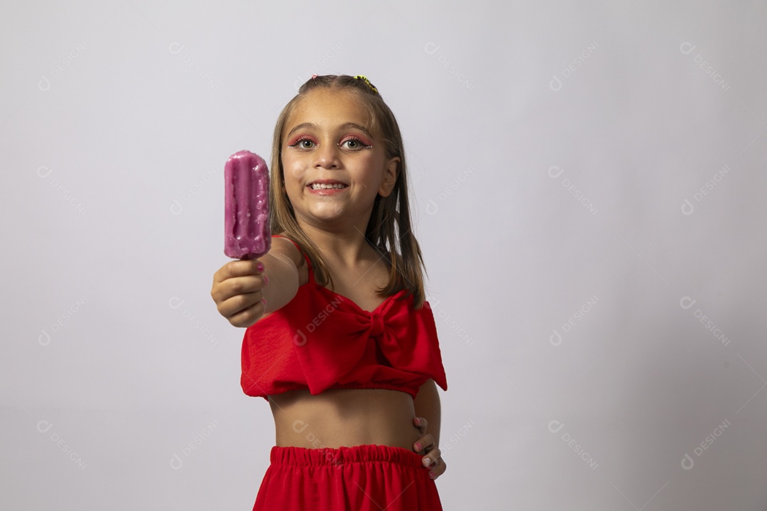 Linda menina com look vermelho segurando picolé sobre fundo de studio isolado